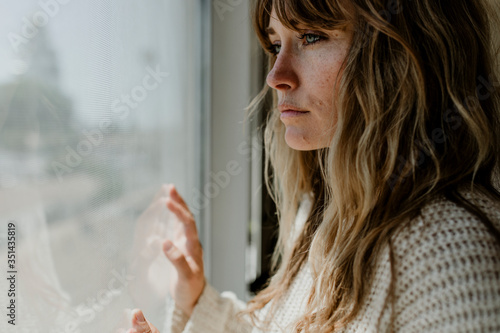 Photographie Sad woman staring out the window during a lockdown