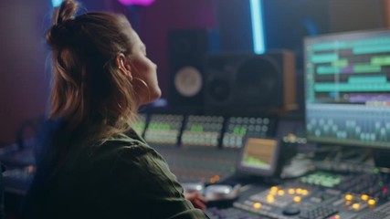 Poster - Female Audio Engineer Working in Music Recording Studio, Uses Mixing Board Create Song. Successful Girl Artist Musician Working at Control Desk. Having Fun, Smiling, Dancing. Handheld Arc Shot