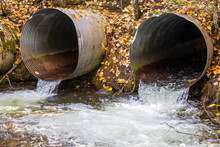 Old Aging Infrastructure. Three Perched Old And Rusty Culverts Creating A Barrier To Fish In A Stream On A Forest Road.