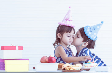 Little boy kissing girl's cheek while celebrating birthday