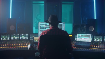 Poster - Producer, Audio Engineer Uses Control Desk for Recording New Album Track in Music Record Studio, in the Soundproof Room Musician, Artist, Performer Sings a Song from New Album. Back View 