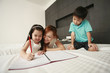 © ImageHit - Girl doing her homework while her mother and brother watching