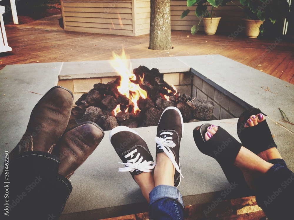 Low Section Of Family Relaxing By Fire Pit - obrazy, fototapety, plakaty 