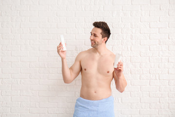 Poster - Handsome man with shower gels on white background