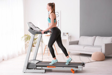 Sporty young woman training on treadmill at home