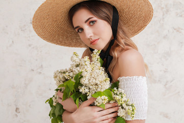 Poster - Beautiful young woman with bouquet of lilac flowers on light background