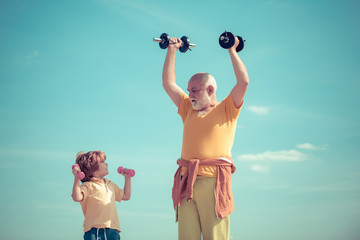 Sports coach and kid building strength with dumbbells. Lifting dumbbells. We exercise every day. Family sport. Boy is doing exercises to develop muscles.