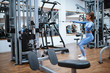 © Dragica - Attractive brunette caucasian girl exercises in the gym on body and arm machine. Fitness woman