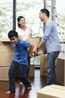© ImageHit - Boy helping parents lifting cardboard box together