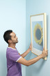 © ImageHit - Man putting up new painting on wall