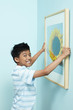 © ImageHit - Boy putting up new painting on wall