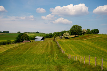 Wall Mural - rural rolling landscape with barns, hay rack, blue sky and clouds in Luxembourg