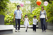 © ImageHit - Family walking hand in hand while holding balloons
