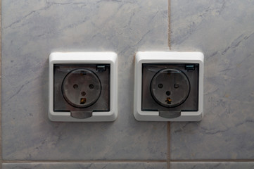 sockets with transparent protective plastic cover on tiled wall