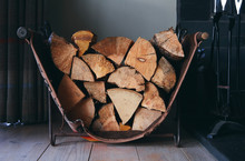 Chopped Logs Stacked In A Rustic Log Holder Beside A Traditional Fireplace.