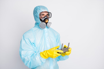 Wall Mural - Photo of doctor man hold joystick control flying drone wear hazmat suit yellow latex rubber gloves goggles breathing mask isolated over gray color background