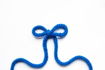 Canvas Print - top view of bow made of blue wool yarn on white background