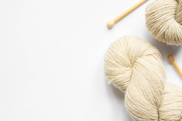 Canvas Print - beige yarn and knitting needles on white background with copy space