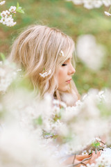 girl in a spring garden admiring flowers. Portrait in profile. Flowers in your hair