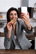 © LIGHTFIELD STUDIOS - selective focus of smiling woman with black dot on palm eating tasty toast bread and taking selfie, domestic violence concept