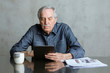 © rawpixel.com - Senior man using social media on tablet with a mug and newspaper on the table