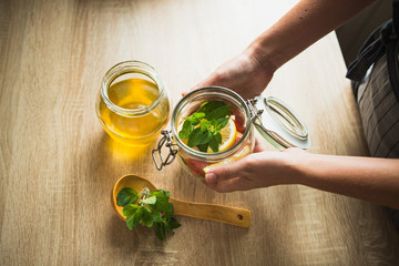 Woman is cooking a drink of mint, honey, lemon, lemon balm and grapefruit.