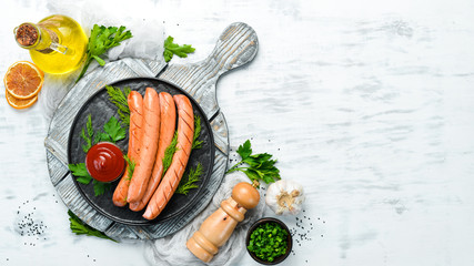 Wall Mural - Boiled sausage with ketchup on a black plate. Top view. Free space for your text.