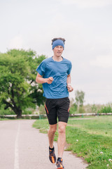 A young athlete in a blue T-shirt runs around the stadium