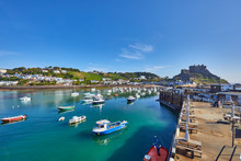Image Of Gorey Harbour With Fishing And Pleasure Boats, The Pier Bullworks And Gorey Castle In The Background With Blue Sky. Jersey, Channel Islands, UK