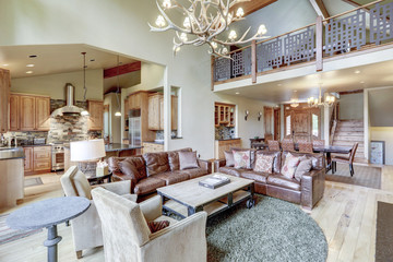 Amazing two story tall living room interior  with sky bridge and leather furniture.