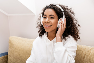 Wall Mural - happy african american girl in wireless headphones listening music at home