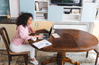 © LIGHTFIELD STUDIOS - curly african american freelancer using laptop near cup, books and documents