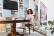© LIGHTFIELD STUDIOS - attractive african american freelancer looking at documents near laptop, books and cup