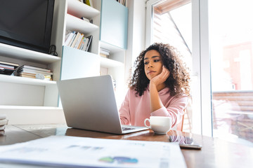 Poster - selective focus of displeased african american freelancer looking at laptop at home