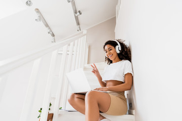 Sticker - african american girl in headphones showing peace sign while having video chat