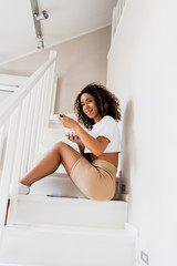 Wall Mural - happy african american woman sitting on stairs and holding breakfast in bowl