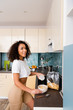 © LIGHTFIELD STUDIOS - cheerful african american woman pouring milk in bowl with cornflakes
