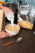 © LIGHTFIELD STUDIOS - cropped view of african american woman pouring milk in bowl with cornflakes