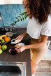 © LIGHTFIELD STUDIOS - attractive and curly african american girl holding toasted bread near jar with jam and fruits on table