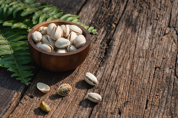 Poster - Pistachio nut in wooden bowl on rusty wood table background