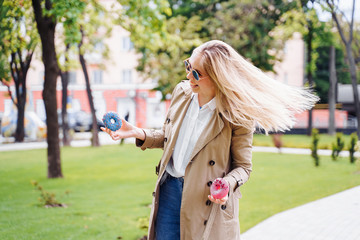 Young woman having fun relaxing at the park holding two delicious donuts with glazing, playful, happy, emotional, expressive, food snack, junk dessert sugar, diet, healthy eating, cheat meal