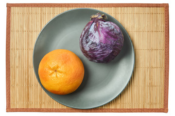 Wall Mural - purple head of red cabbage and rosy yellow grapefruit on a gray plate on a cane tablecloth