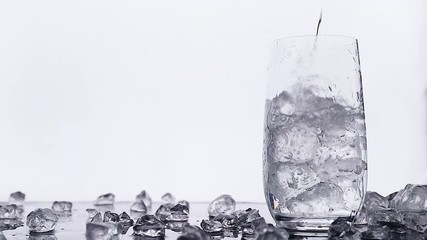 Wall Mural - pouring water into glass with ice isolated on white background with copy space