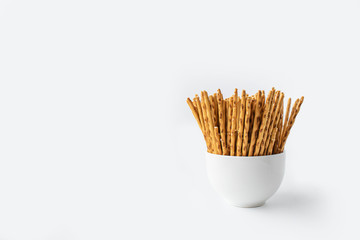 Crispy cookies in the form of sticks in a white Cup on a white background