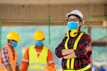 Poster - Builders wearing safety helmet with blueprint at construction,Concept of residential building under construction.