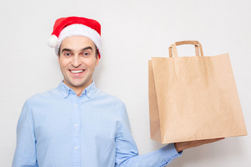 Wall Mural - Concept of a new year. Man in Santa Claus hat with gift bag, portrait, white background, copy space