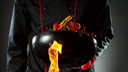 Wall Mural - Super slow motion of flying chilli peppers from wok pan, chef closeup. Filmed on high speed cinema camera, 1000 fps.