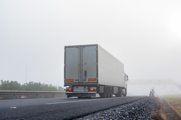 Wall Mural - Truck with refrigerated semi-trailer driving on the highway on a thick foggy day