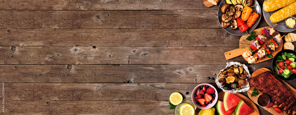 Summer BBQ or picnic food corner border over a rustic wood banner background. Assorted grilled meats, vegetables, fruits, salad and potatoes. Overhead view with copy space. - obrazy, fototapety, plakaty 