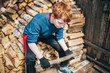 © andrey gonchar - The boy was tired of chopping wood and sat down to rest with an ax in his hands - helps parents with the housework